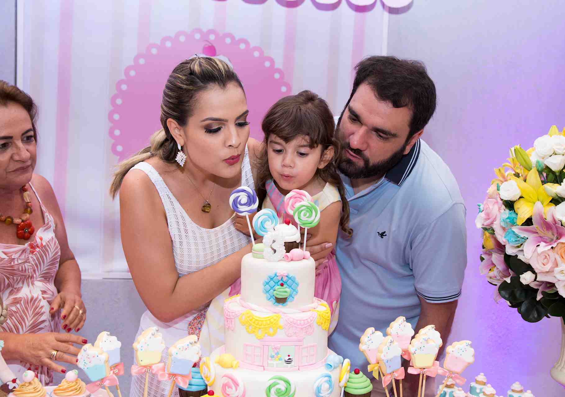 Retrato da pequena Bianca e seus pais, assoprando a vela do bolo de aniversário
